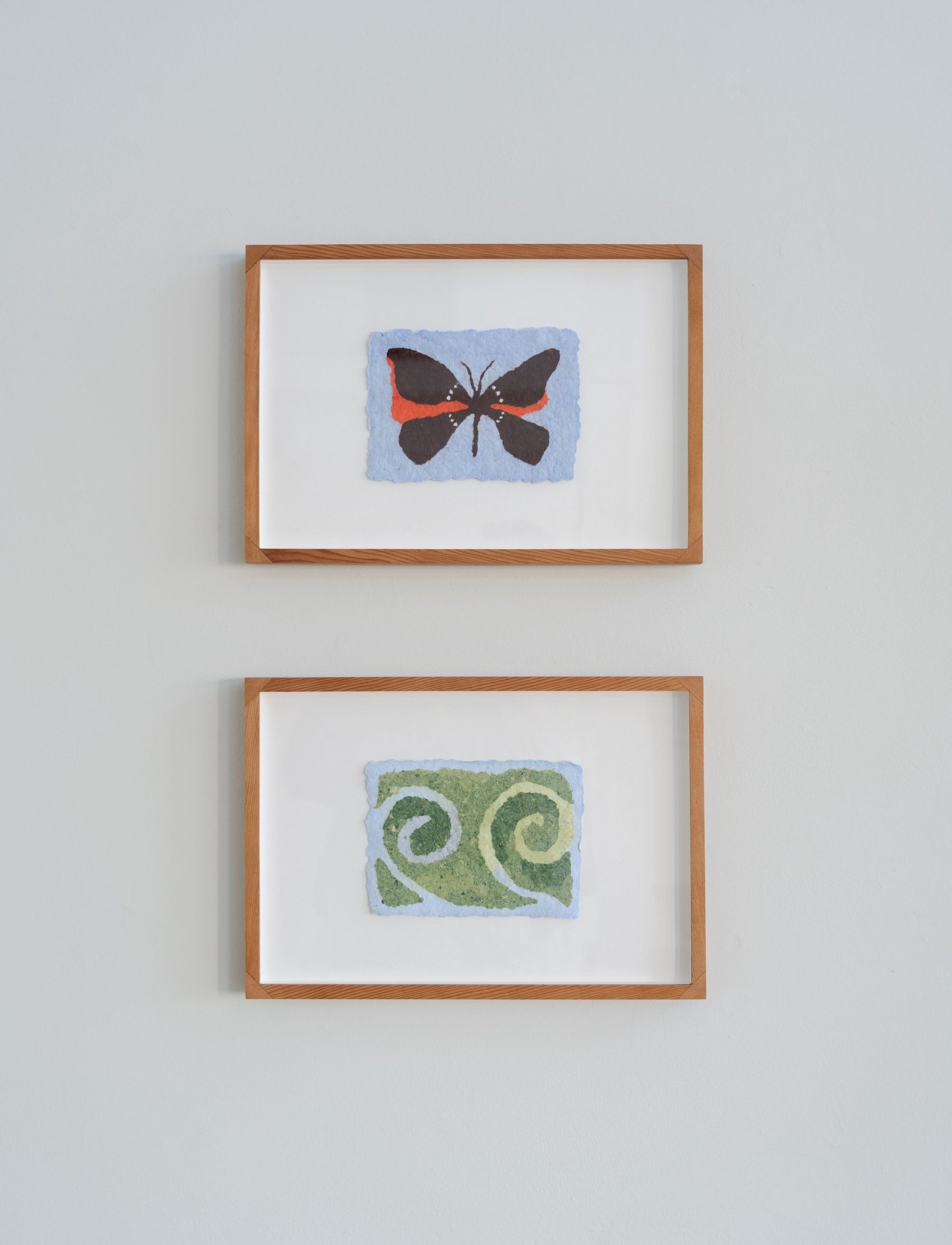 two stacked pulp pieces made from discarded cotton t-shirts, one a butterfly and the other two spiraling plants